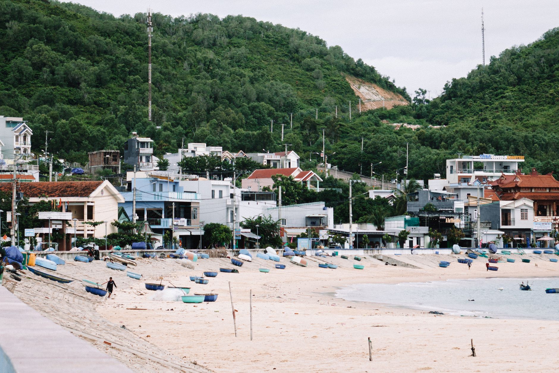 Sandy beach with traditional round fishing boats and green hills, Quy Nhon coastal town, central Vietnam