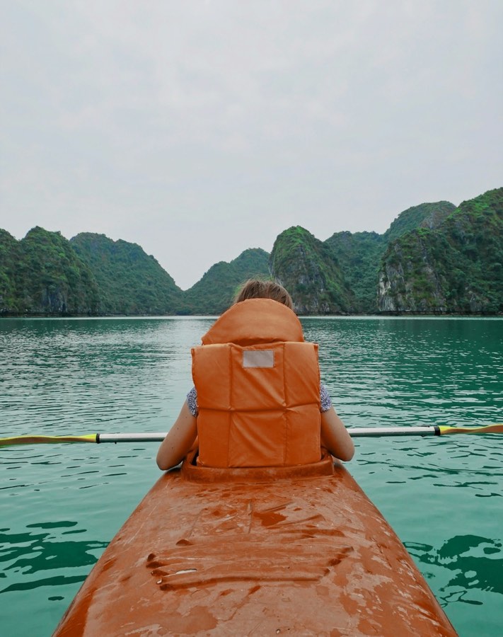 Kayaker in life vest paddling near limestone islands