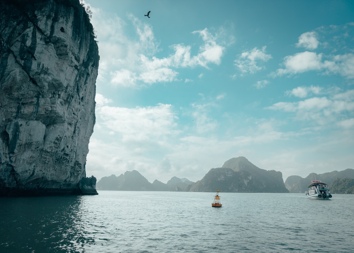 Limestone karsts rising from a calm bay with a boat, Vietnam