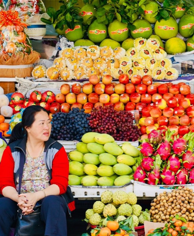 Woman at a colourful fruit and vegetable stand at Da Lat market, Vietnam