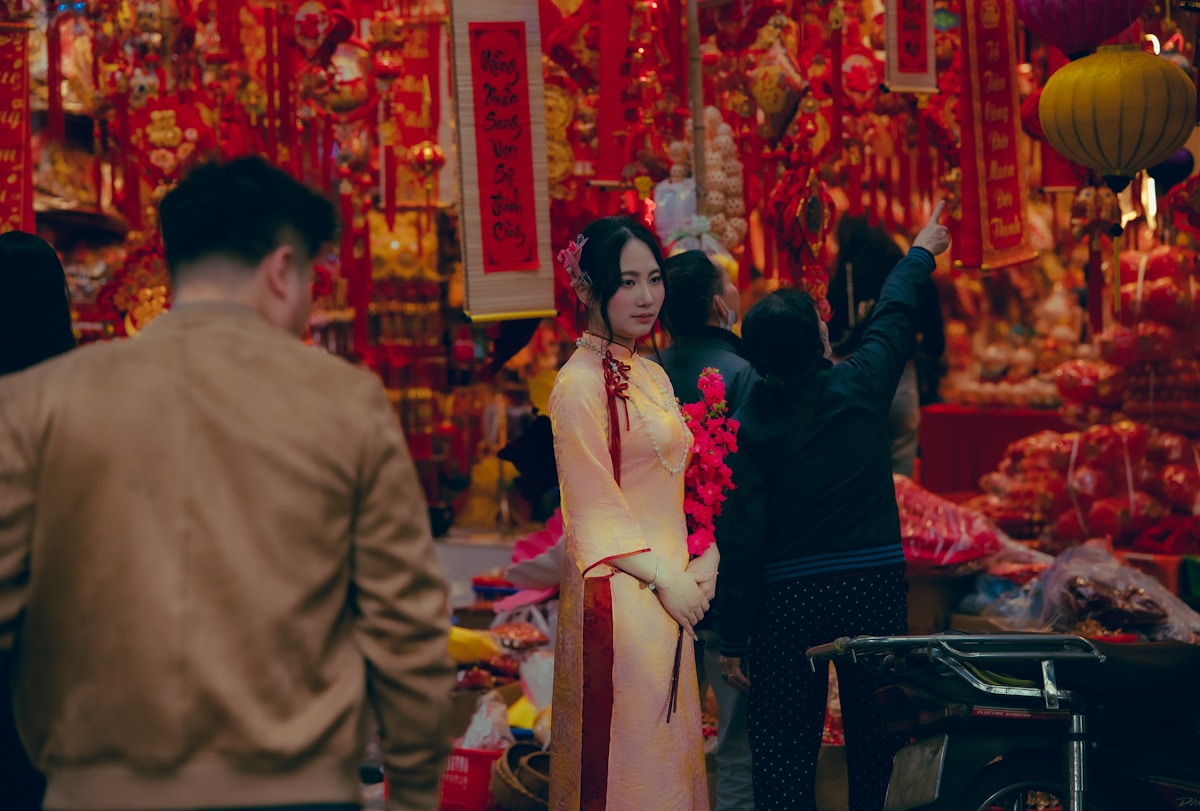 Woman in áo dài at a Tết flower and decoration market in Hanoi's Old Quarter, Vietnam