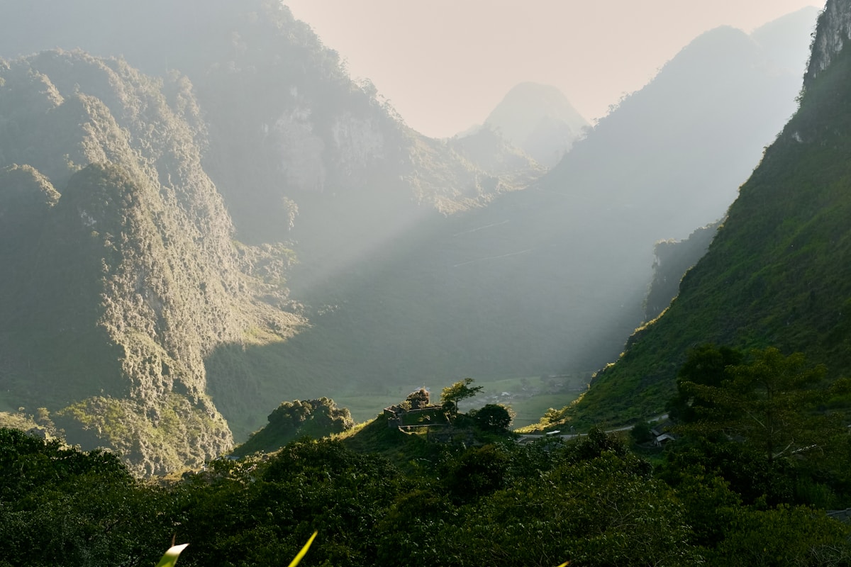 Sunlight streaming through misty green mountain valleys, Ha Giang