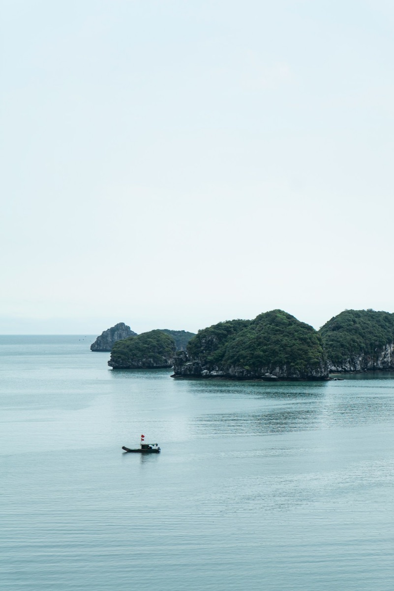 Person on a boat on the sea near limestone karsts, Ha Long Bay, Vietnam