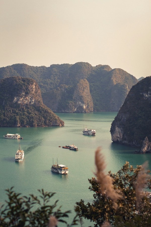 Boats floating on Ha Long Bay surrounded by limestone mountains, Vietnam