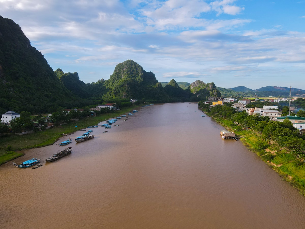 River flowing past green karst mountains with boats, Vietnam