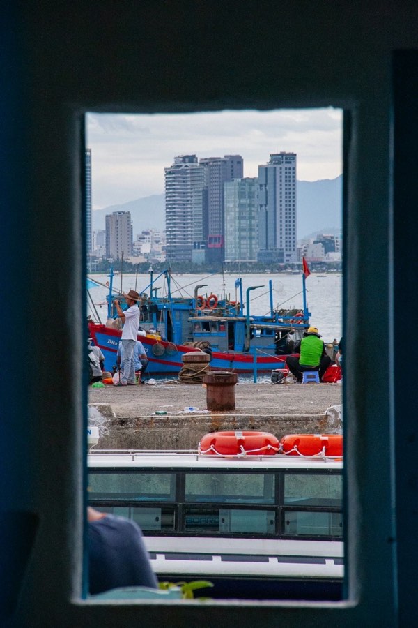 Boats docked at a pier with city skyline, Hai Phong, Vietnam
