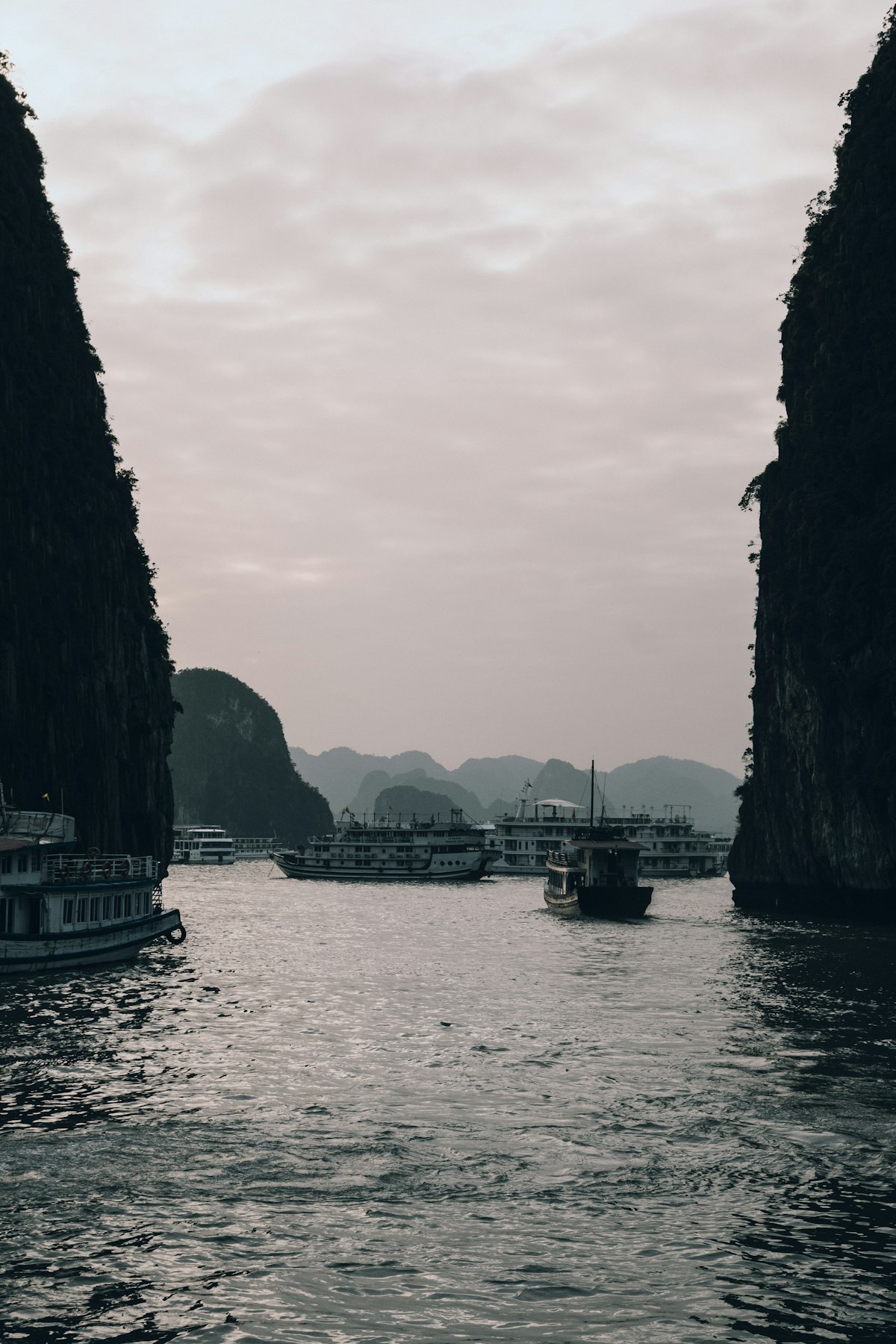 Cruise boats navigating between limestone karsts in Ha Long Bay at dusk