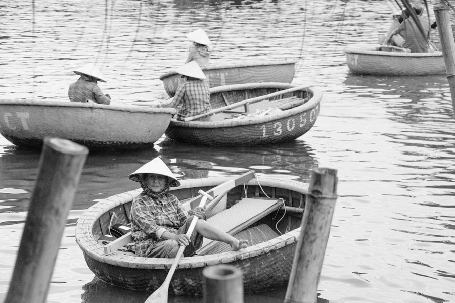 People wearing conical hats rowing traditional round boats on the water, Hoi An, Vietnam