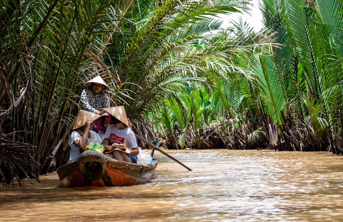 Tourists in a traditional sampan boat gliding through palm-lined Mekong Delta canals