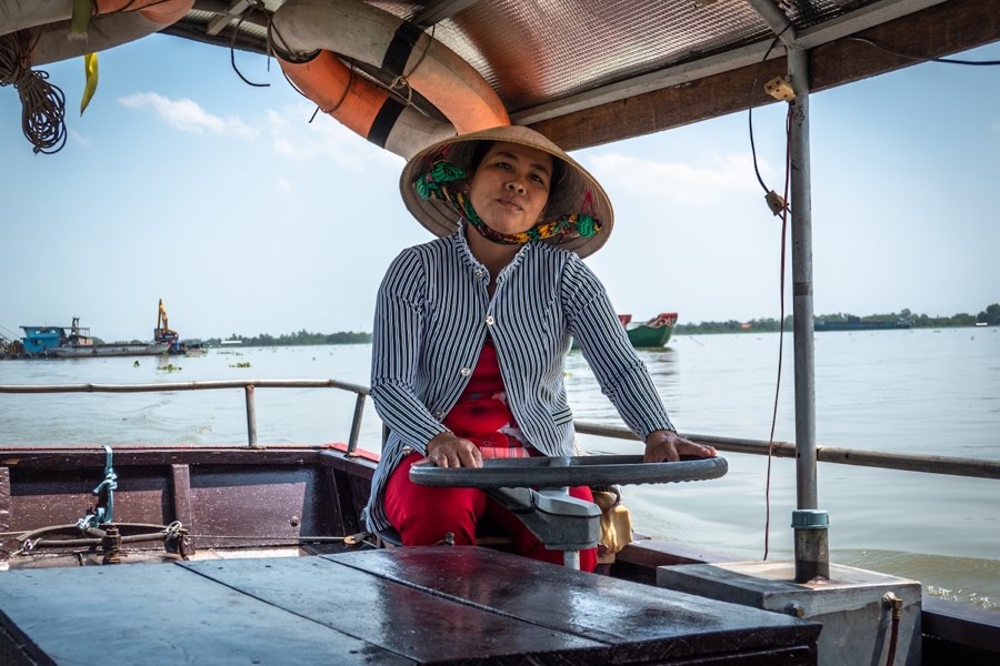 Woman rowing a wooden boat through the Mekong Delta, Vietnam