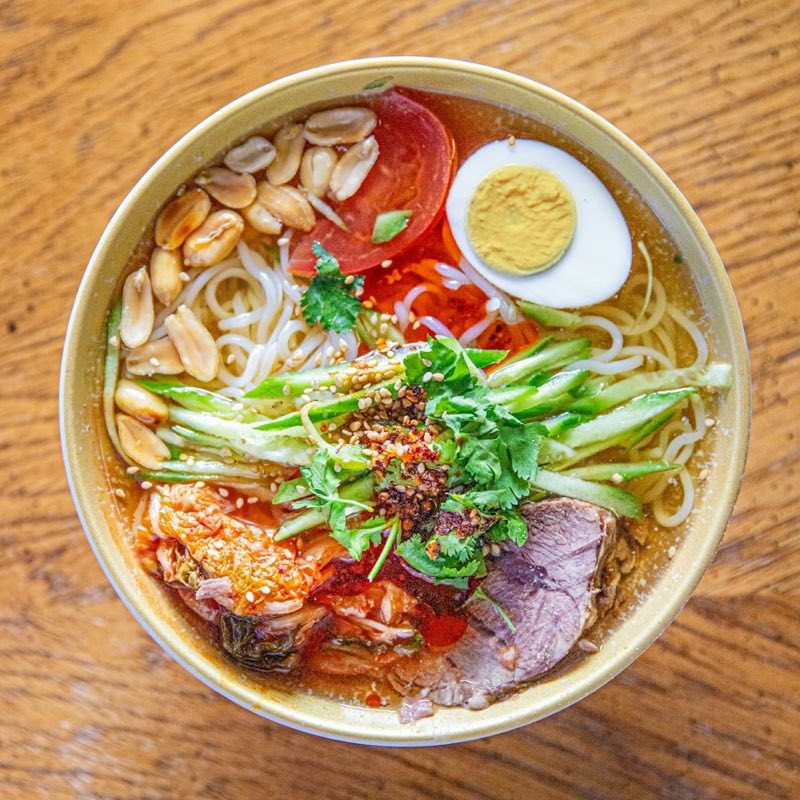 Bowl of Vietnamese noodle soup with chopsticks on a red plastic table at a street food stall, northern Vietnam