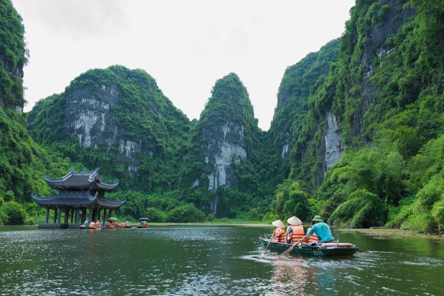 Group of visitors in a small boat through Trang An, Ninh Binh, Vietnam
