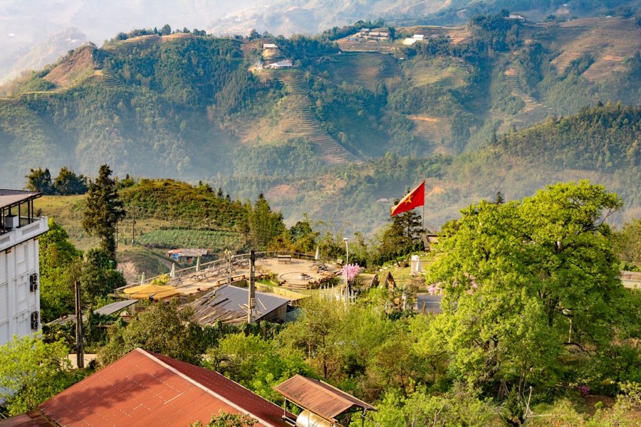 Vietnamese flag flying over a hill with terraced valley and mountains, Sapa, Vietnam