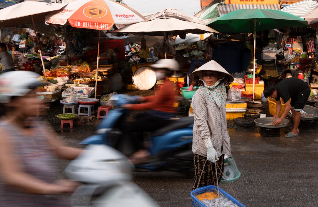 Woman in conical hat selling goods at a busy street market in Phu Quoc, Vietnam