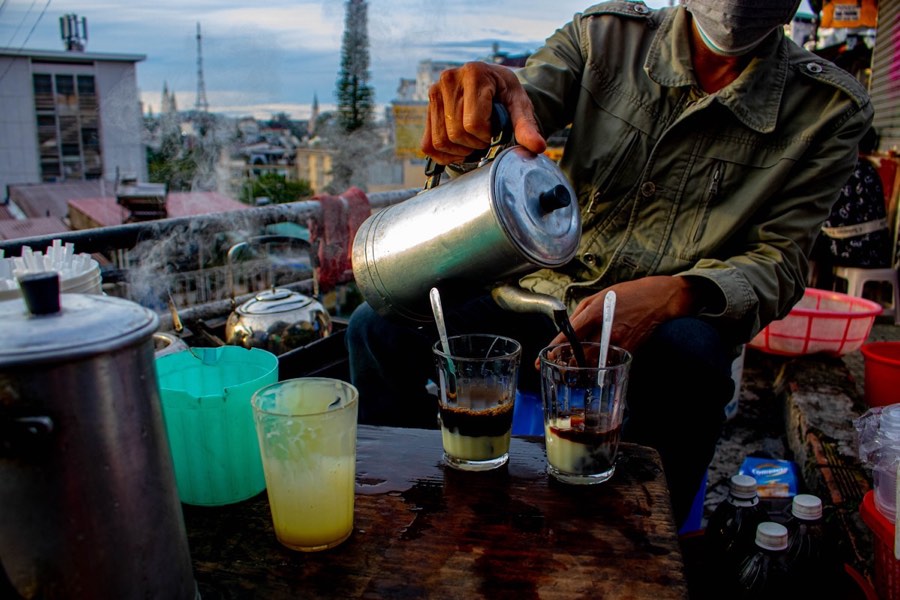 Vietnamese coffee with cream topping, notebook and camera on a wooden table