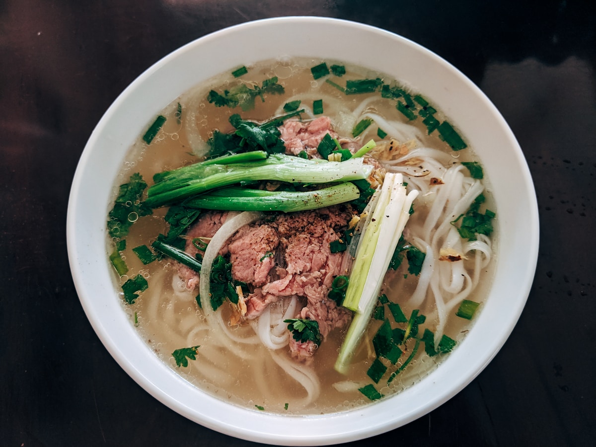 Bowl of Vietnamese beef noodle soup with fresh herbs and chopsticks
